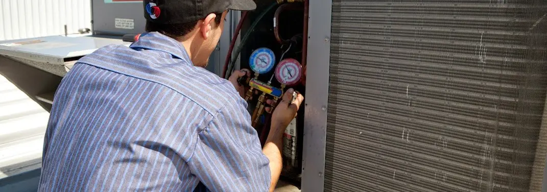 HVAC technician servicing a condenser unit in Stroud